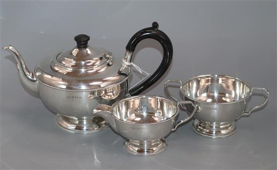 A George V silver three-piece tea service, of circular bead-edged form, Birmingham, 1931, gross 20 oz.
